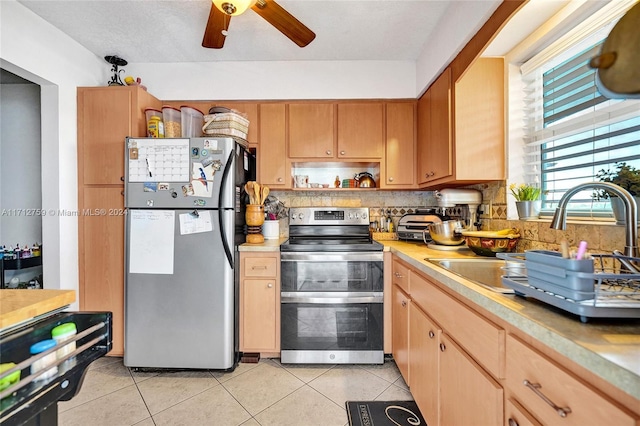 kitchen featuring ceiling fan, sink, backsplash, light tile patterned flooring, and appliances with stainless steel finishes