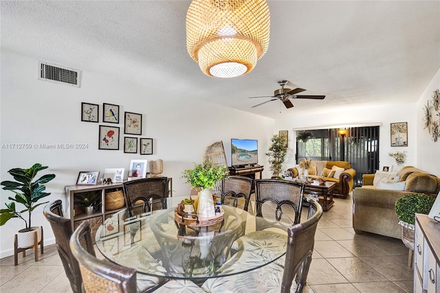 tiled dining area with ceiling fan and a textured ceiling