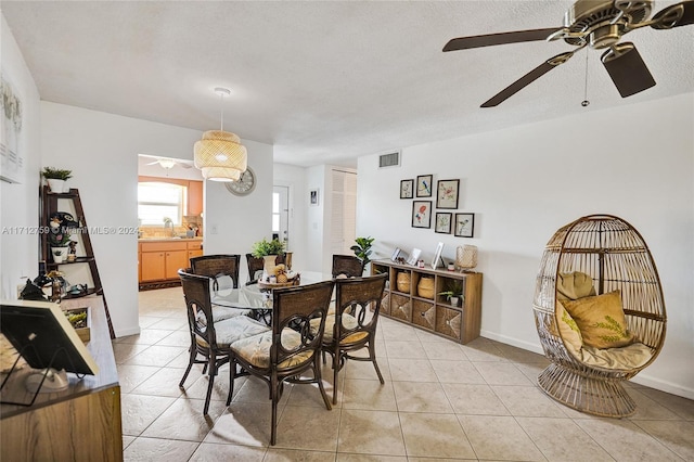 tiled dining space featuring ceiling fan, sink, and a textured ceiling