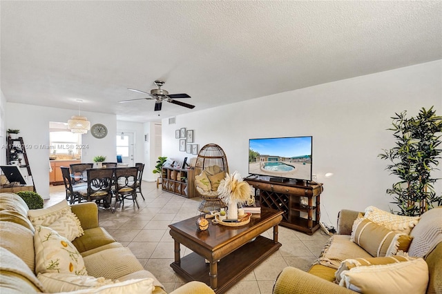 living room with ceiling fan, light tile patterned floors, and a textured ceiling