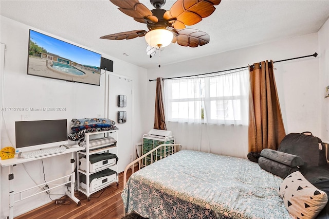 bedroom with ceiling fan, dark wood-type flooring, and a textured ceiling