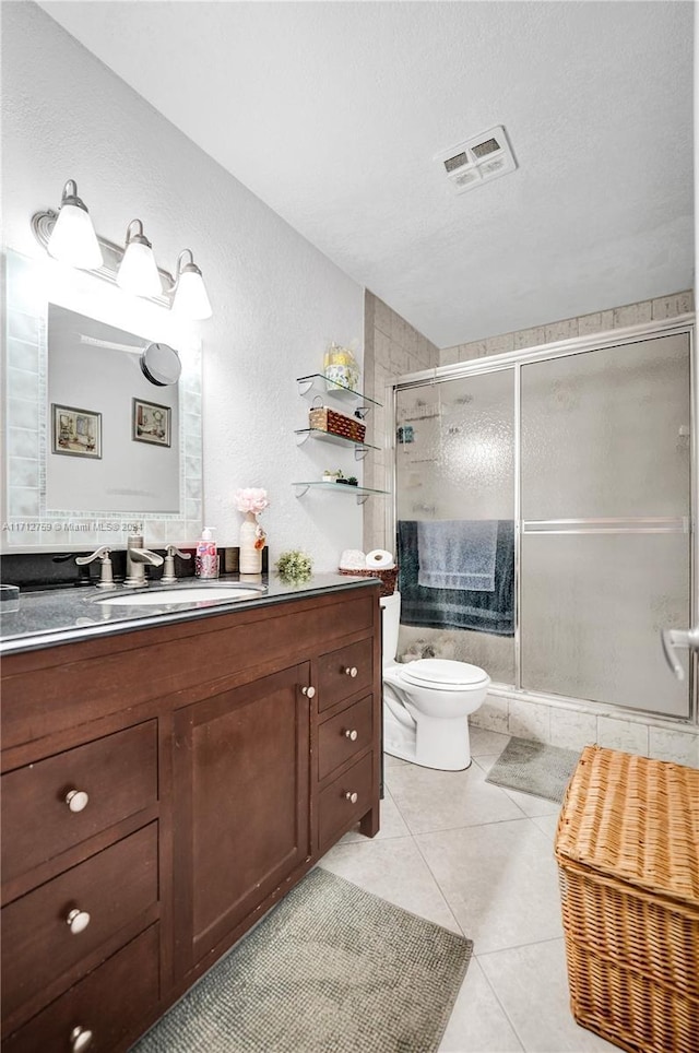 bathroom with vanity, a shower with door, tile patterned flooring, toilet, and a textured ceiling