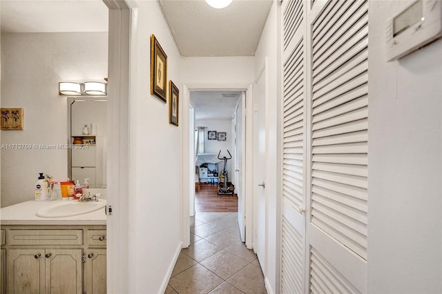 hall featuring light tile patterned floors, a textured ceiling, and sink