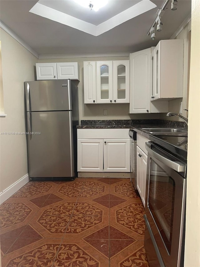 kitchen with stove, rail lighting, sink, white cabinetry, and stainless steel refrigerator