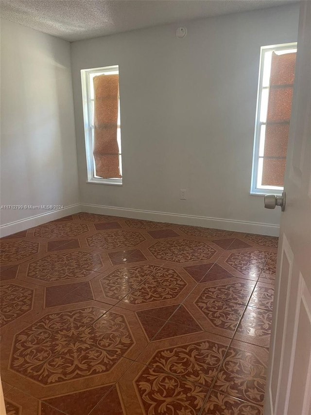 tiled empty room featuring a textured ceiling