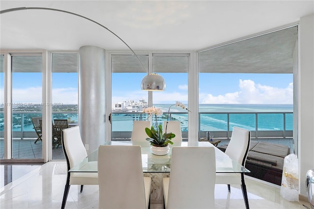 tiled dining room featuring a water view and a wall of windows