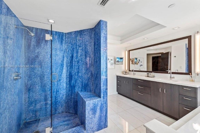 bathroom featuring a raised ceiling, vanity, tile patterned floors, and walk in shower