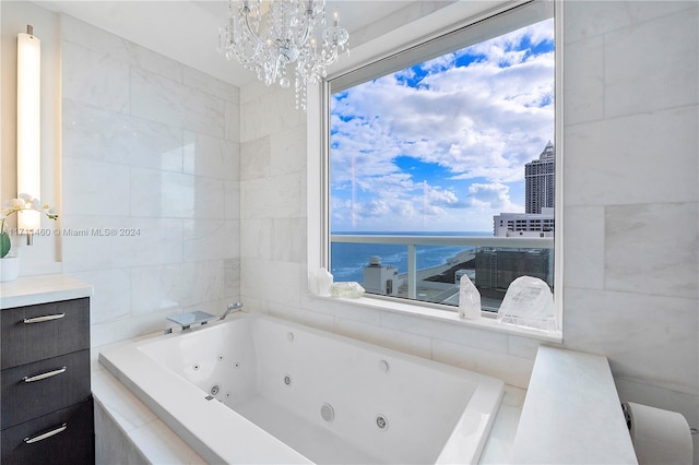 bathroom featuring tiled tub, a water view, and an inviting chandelier