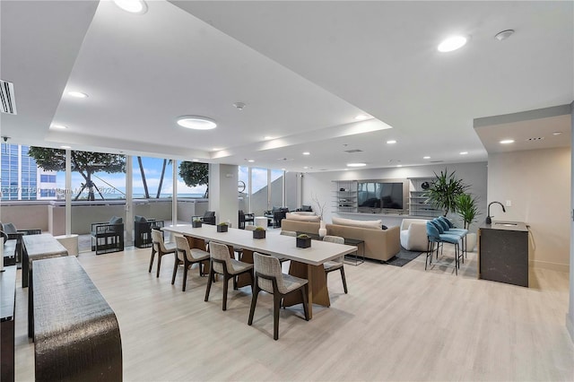 dining area featuring light wood-type flooring and a tray ceiling