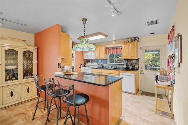 kitchen with pendant lighting, white appliances, a kitchen breakfast bar, tasteful backsplash, and light brown cabinetry