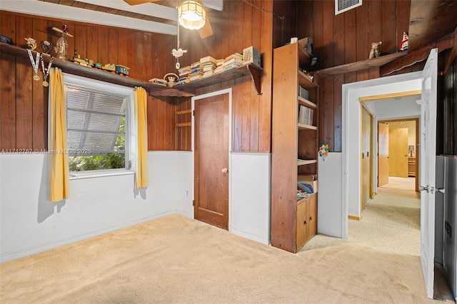 unfurnished bedroom with light colored carpet, lofted ceiling, and wood walls