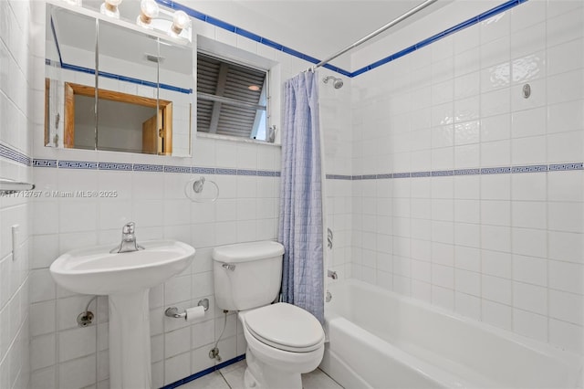 bathroom featuring toilet, shower / tub combo, and tile walls