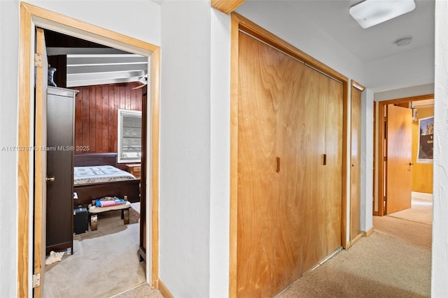 hall featuring light colored carpet and wood walls