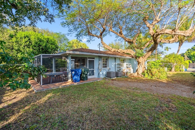 rear view of house with a yard, central AC, and a sunroom