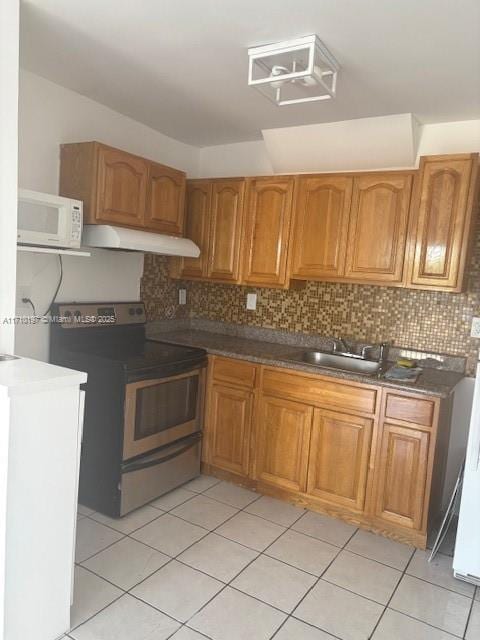 kitchen with electric stove, white microwave, brown cabinets, under cabinet range hood, and a sink