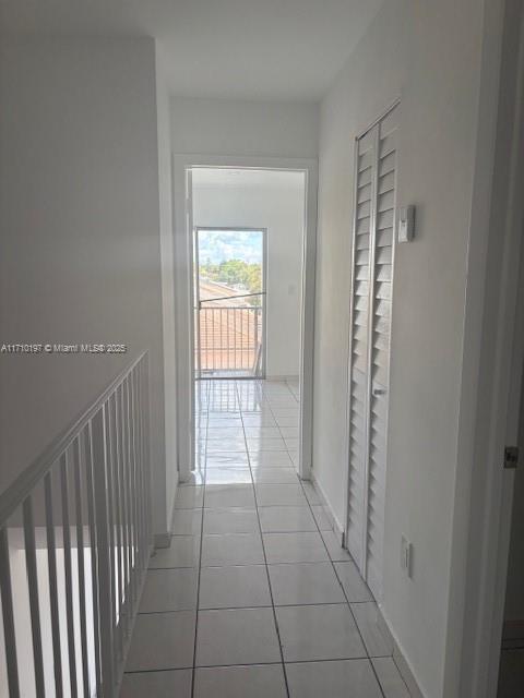 hallway with baseboards and light tile patterned flooring