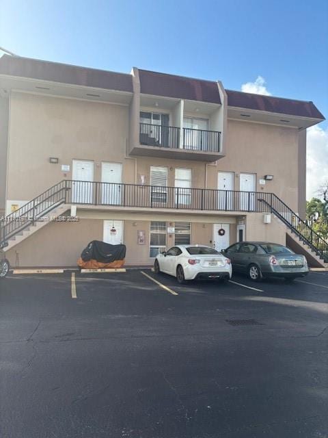 view of building exterior featuring stairs and uncovered parking