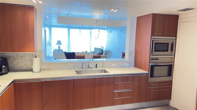 kitchen featuring appliances with stainless steel finishes, sink, light wood-type flooring, and decorative backsplash