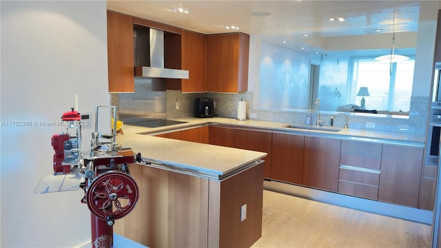 kitchen with sink, backsplash, black electric stovetop, kitchen peninsula, and wall chimney range hood