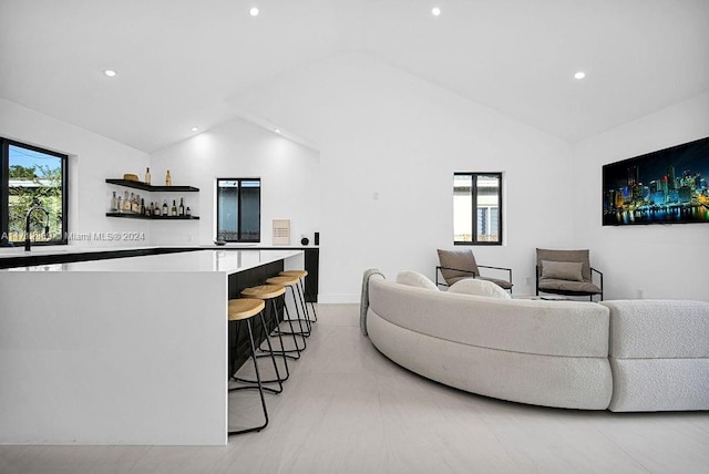 living room with lofted ceiling, sink, and a wealth of natural light