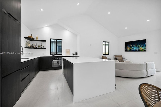 kitchen featuring oven, a center island, and high vaulted ceiling