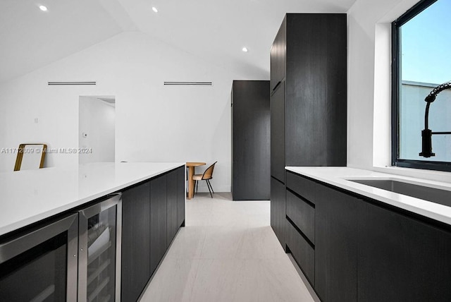 kitchen with sink, beverage cooler, and lofted ceiling