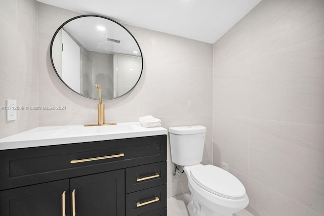 bathroom with vanity, tile walls, and toilet