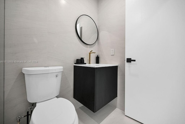 bathroom with vanity, toilet, and tile walls