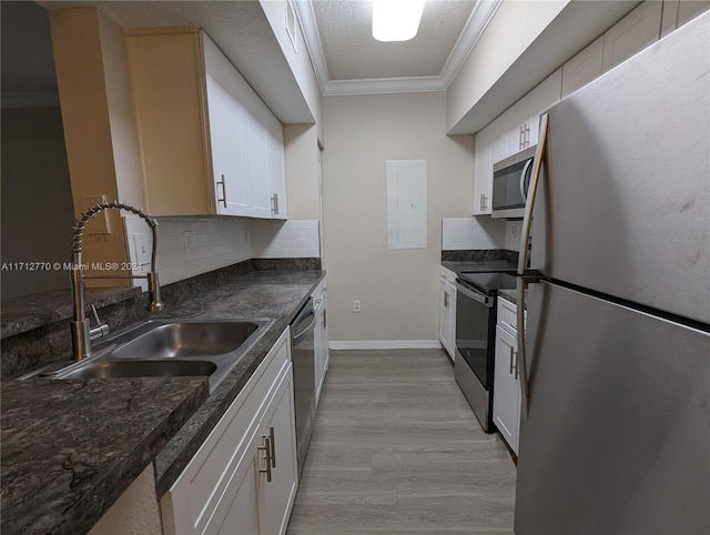 kitchen with ornamental molding, stainless steel appliances, sink, light hardwood / wood-style flooring, and white cabinetry