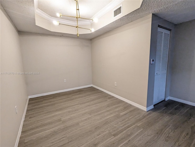 spare room featuring a textured ceiling, hardwood / wood-style flooring, a raised ceiling, and ornamental molding