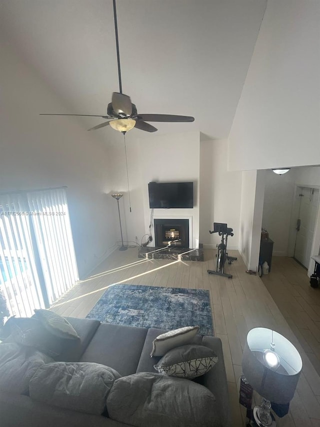 living room featuring ceiling fan, a high ceiling, and hardwood / wood-style flooring