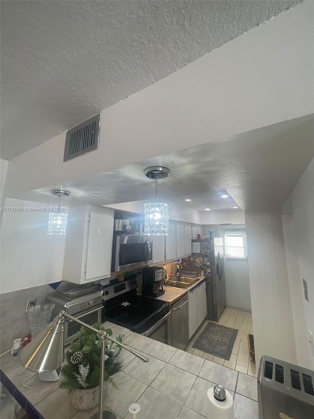 4075 Coral Springs Dr Unit 5, Coral Springs, FL 33065 - kitchen featuring a textured ceiling, visible vents, white cabinetry, appliances with stainless steel finishes, and light tile patterned floors