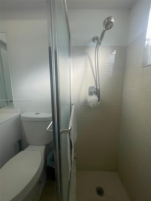 bathroom featuring a tile shower, toilet, and tile patterned floors