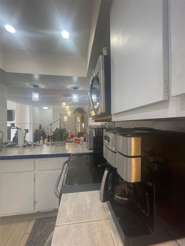 kitchen with white cabinets, tile counters, and range