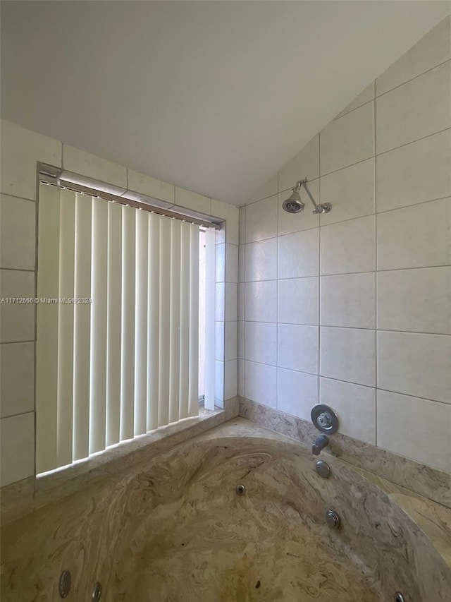 bathroom featuring lofted ceiling and washtub / shower combination