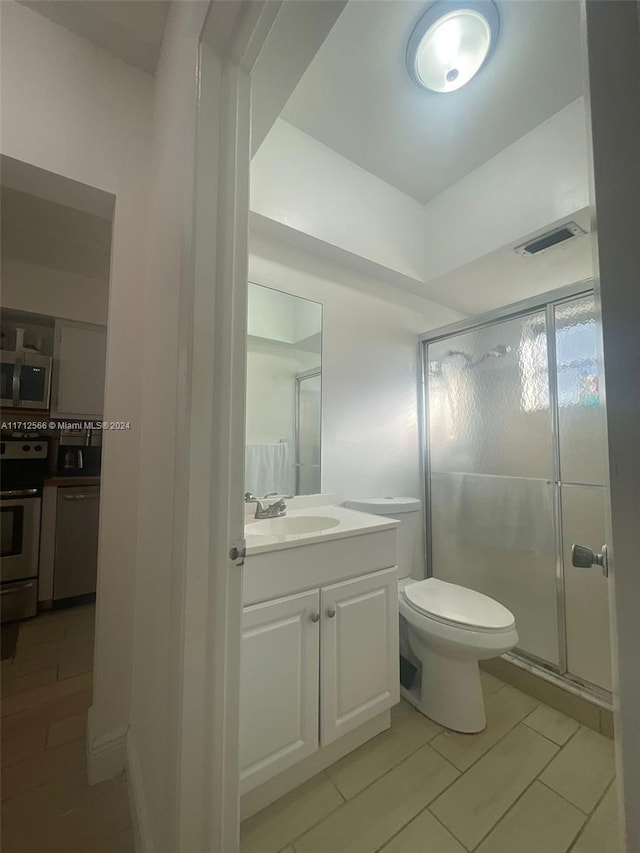 bathroom featuring tile patterned floors, vanity, an enclosed shower, and toilet