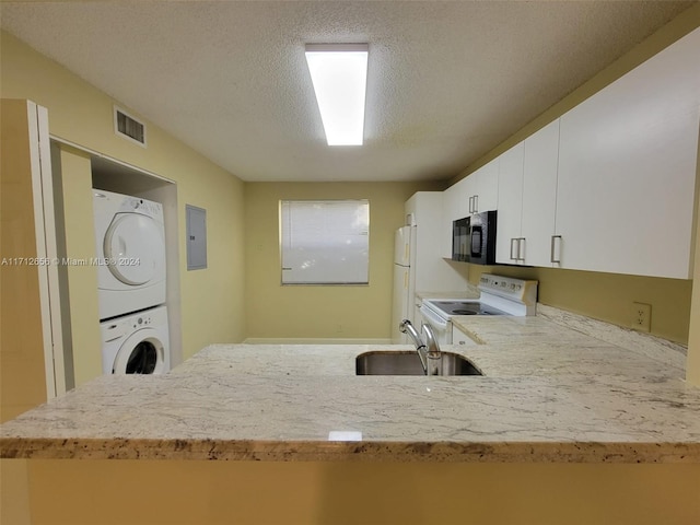 kitchen featuring white appliances, stacked washer and dryer, sink, a textured ceiling, and white cabinetry