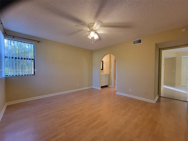 spare room featuring a textured ceiling, light hardwood / wood-style floors, and ceiling fan