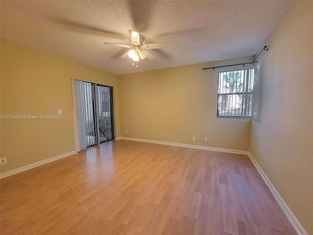 empty room with ceiling fan, light wood-type flooring, and a textured ceiling