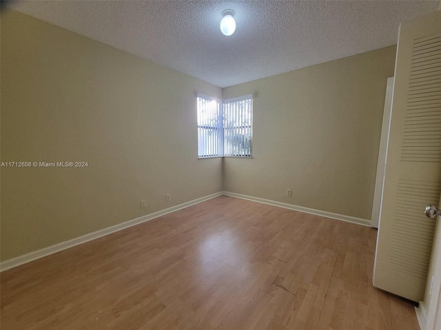 unfurnished room with a textured ceiling and light hardwood / wood-style floors