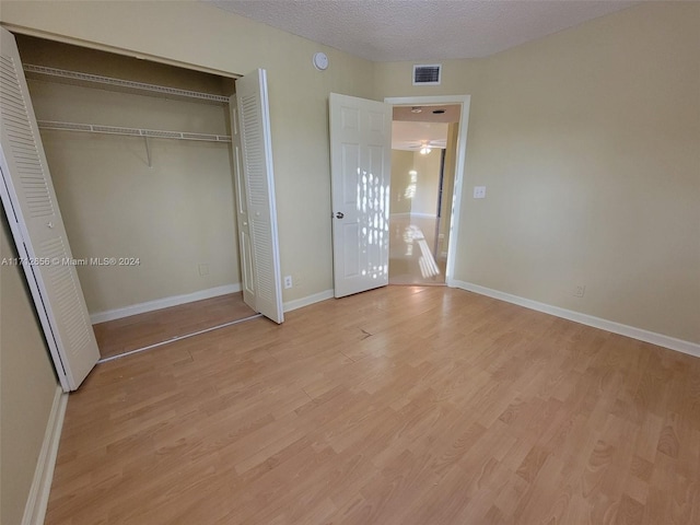 unfurnished bedroom with a textured ceiling and light hardwood / wood-style flooring