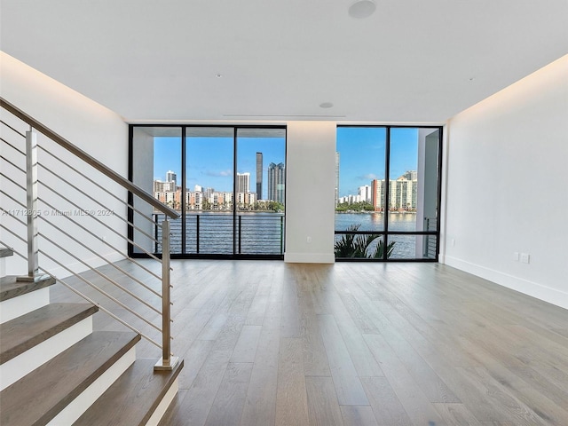 spare room with hardwood / wood-style flooring, a healthy amount of sunlight, and a wall of windows