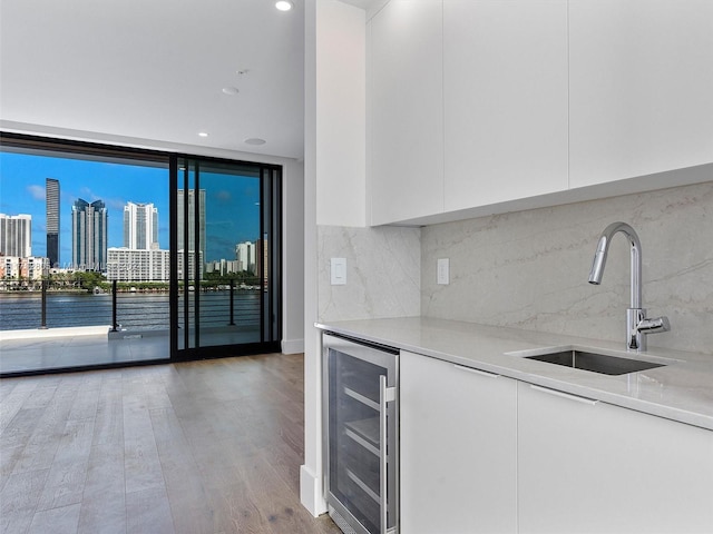 kitchen with white cabinets, decorative backsplash, beverage cooler, and sink