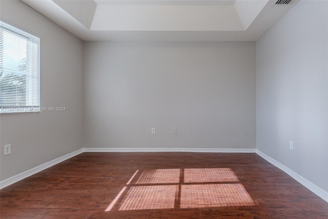 empty room featuring dark hardwood / wood-style floors and a raised ceiling