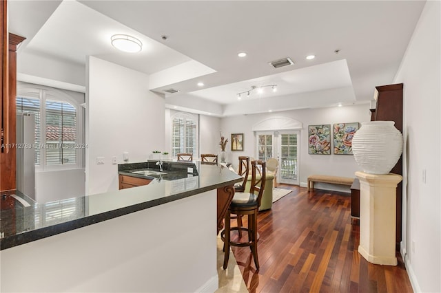 kitchen with sink, kitchen peninsula, dark wood-type flooring, and a breakfast bar area