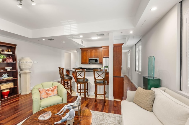 living room with dark hardwood / wood-style flooring and a tray ceiling