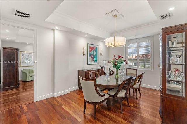 dining room featuring a raised ceiling, ornamental molding, dark hardwood / wood-style floors, and an inviting chandelier