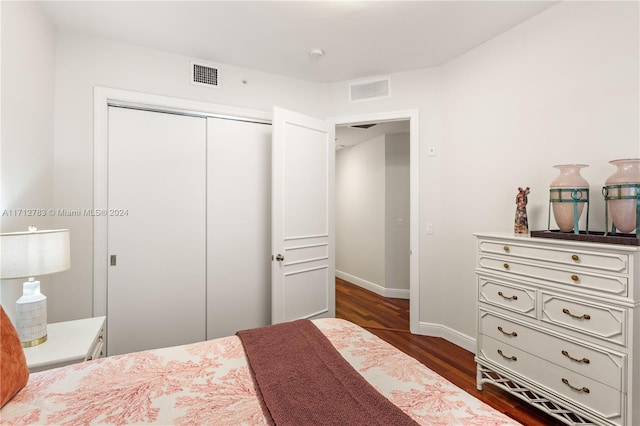 bedroom with dark hardwood / wood-style floors and a closet