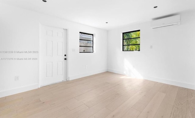 spare room featuring a wall mounted AC and light wood-type flooring