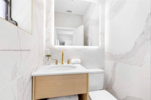 bathroom featuring vanity, toilet, and tile walls